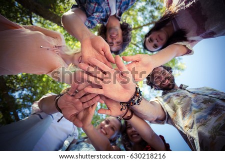 Smiling friends forming a handstack in park on a sunny day