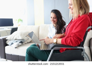 Smiling friends looking at photos on laptop, woman in wheelchair and disabled people