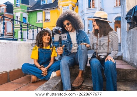 Smiling friends making a vlog using a smartphone with microphone and gimbal in a colorful neighborhood
