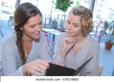 smiling friends using a tablet in the cafe