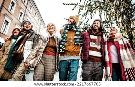 Smiling friends walking embraced on the city - Happy group of young people enjoying the day standing outside in winter clothes - Friendship concept with boys and girls laughing during xmas holidays	