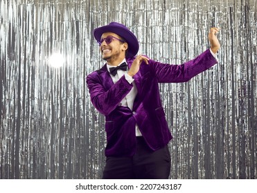 Smiling Funny African American Man Magician In Costume Make Tricks Entertain Public. Happy Young Black Male Entertainer In Suit And Hat Isolated On Glitter Disco Background In Night Club.