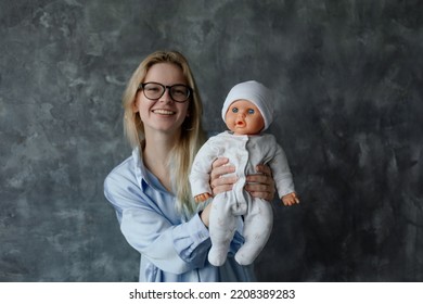 Smiling Future Mother Take Birth Preparation Course, Gray Wall Background, Free Copy Space. Successful Mastering Of Practical Skills Of Newborns Care. Training For Pregnant Women, Practice On Doll.