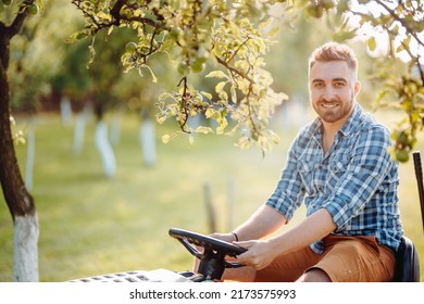 Smiling Gardener Riding A Tractor And Cutting Grass