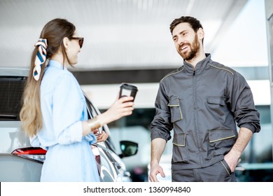 Smiling Gas Station Worker In Uniform Talking With Woman Client At The Petrol Station Outdoors