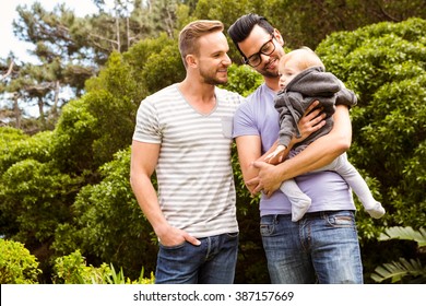 Smiling Gay Couple With Child In Garden