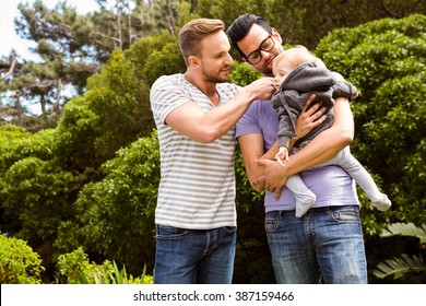 Smiling Gay Couple With Child In Garden