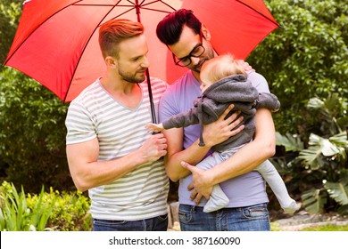 Smiling Gay Couple With Child In Garden