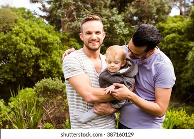 Smiling gay couple with child in garden