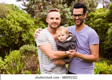 Smiling Gay Couple With Child In Garden