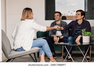 Smiling gay couple meeting with a real estate agent, shaking hands to finalize a home purchase. - Powered by Shutterstock