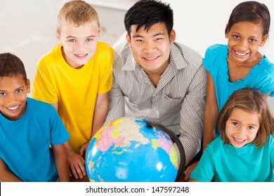 smiling geography teacher with group of adorable primary students - Powered by Shutterstock