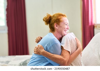 Smiling Geriatric Nurse Lovingly Hugging Old Sick Woman In Nursing Home Or Hospital