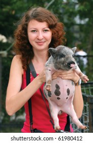 Smiling ginger girl holding piglet