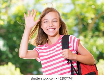 Smiling Girl 10-11 Year Old Stretching Her Hand Up For Greeting .Beautiful Schoolgirl With Backpack Posing Outdoors. Young Student Beginning Of Class After Vacation.