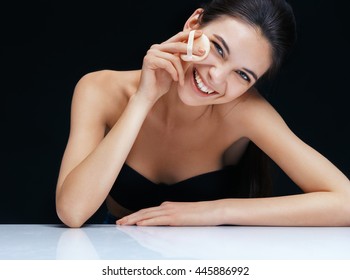 Smiling girl applying powder. Portrait of brunette woman toothy smile on black background. Youth and skin care concept