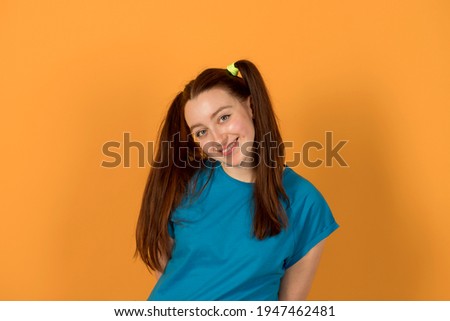 Smiling girl in a blue shirt on a yellow background. 1 april fools day