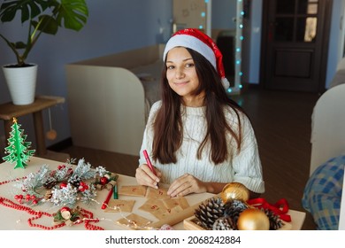 A Smiling Girl In A Christmas Hat Makes An Advent Calendar. High Quality Photo