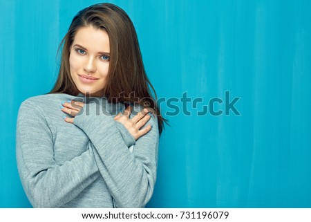Smiling girl crossed arms on breast. Isolated portrait on blue back wall.