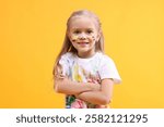 Smiling girl with crossed arms smeared in paint on orange background