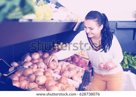 
Smiling girl deciding on onions in grocery shop