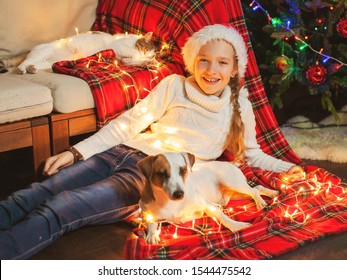 Smiling girl with dog and cat near christmas tree at home. Merry christmas and happy New year!