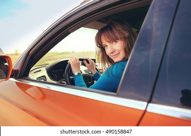 Smiling Girl Driving An Orange Car