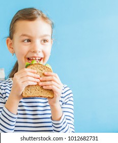 Smiling Girl Eating Healthy Sandwich With Salad And Avocados