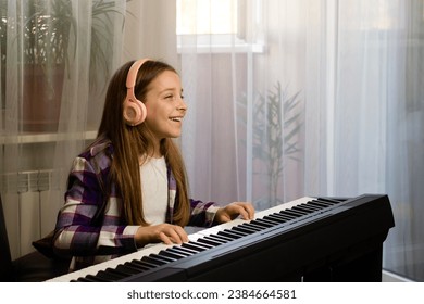 Smiling girl with headphones playing piano at home, enjoying her music practice session - Powered by Shutterstock