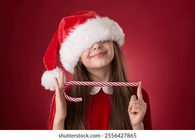 Smiling girl hold Christmas candy cane and wear red Santa Claus hat as Snow White portrait in red background - Powered by Shutterstock