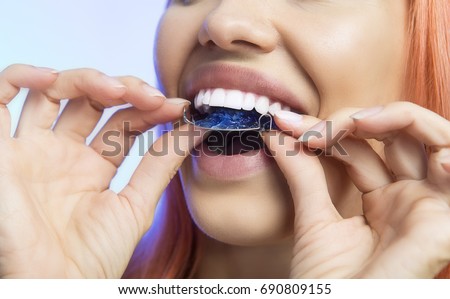 Smiling Girl Holding blue Retainer, Braces for Teeth. Orthodontics Dental Theme, Methods of Teeth (Bite) Correction, Close-up