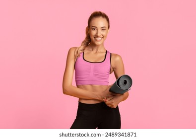 Smiling Girl Holding Fitness Mat Looking At Camera Standing Over Yellow Background. Studio Shot - Powered by Shutterstock