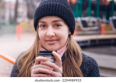 Smiling girl holding a hot drink outside on a cold day