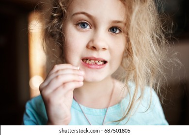 Smiling Girl Holding Missing Milk Tooth, Close Up Photo.