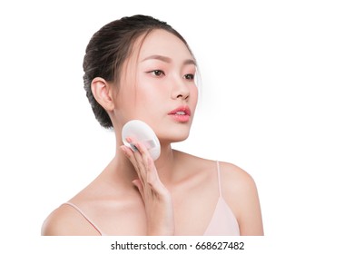 Smiling girl holding powder cushion puff applying cosmetic powder on face