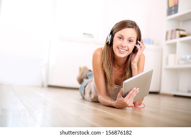 Smiling Girl Laying On The Floor And Listening To Music