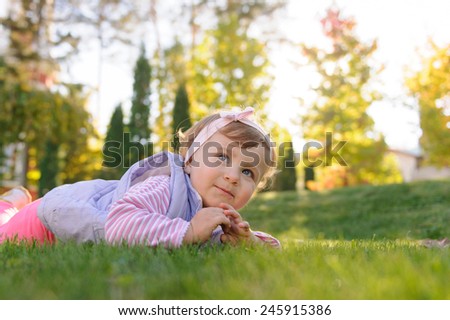 Similar – Littel girl sitting on grass looking curious