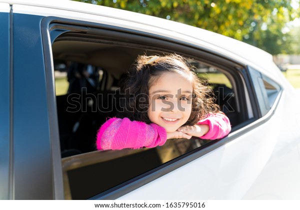Smiling Girl Leaning On Car Window While Making Eye\
Contact During Sunny\
Day