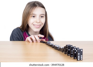 Smiling Girl Looking At Black Dominoes Falling Down On Wooden Board Isolated On White Background