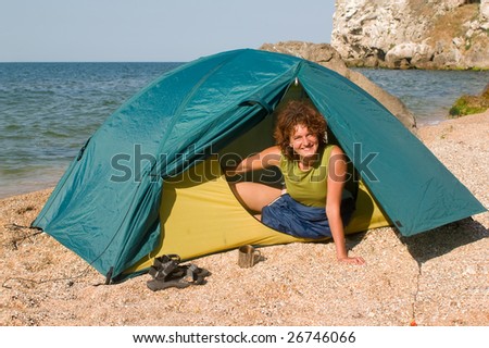 Smiling girl looking from a tent at seaside