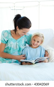 Smiling Girl On A Hospital Bed Reading With Her Mother