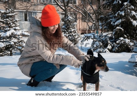 smiling girl play with dog in winter. girl pet lover playing with her dog. girl outside with dog. playful dog outdoor with girl.