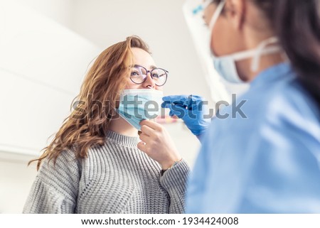 Smiling girl puts face mask off her nose so that a healthcare worker can take a sample for Covid-19 testing.
