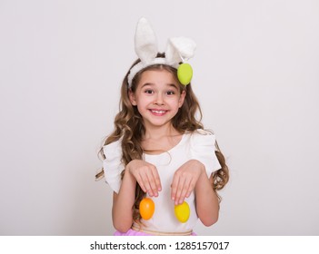 Smiling girl with rabbit ears and easter eggs on pink background. Easter bunny concept. - Shutterstock ID 1285157017