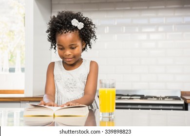 Smiling girl reading a book in the kitchen