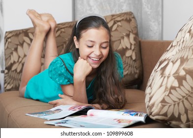 The Smiling Girl Reading On The Brown Sofa