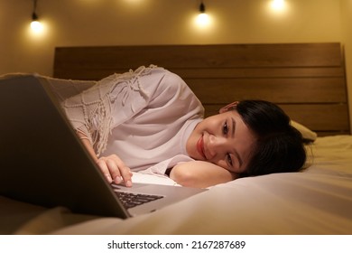 Smiling Girl Resting On Bed And Watching Romantic Comedy Movie On Laptop