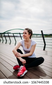 Smiling Girl In Sportwear Sitting On Dock.