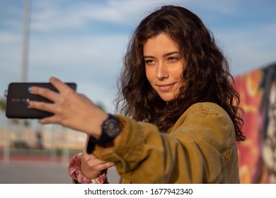 A Smiling Girl Taking A Selfie At A Skatepark During The Golden Hour