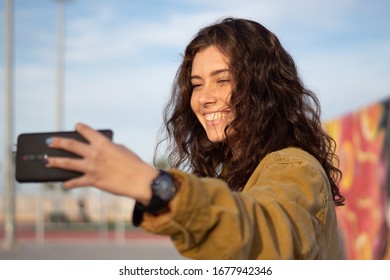 A Smiling Girl Taking A Selfie At A Skatepark During The Golden Hour